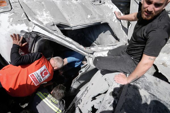 Спасатели осматривают сгоревший автомобиль на месте израильского авиаудара по многоквартирному дому в Бейруте.