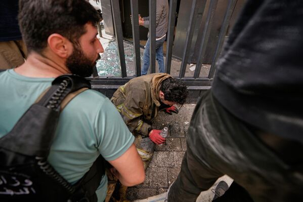 Пожарный, надышавшийся дыма, на месте израильского авиаудара по многоквартирному дому в Бейруте.